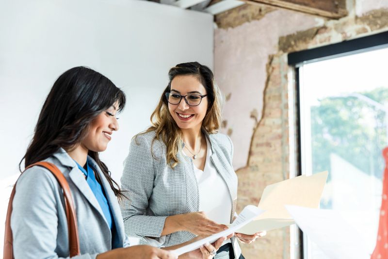 Smiling colleagues collaborating, reviewing paperwork.  Successful teamwork, business meeting.