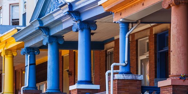Colorful columns line the porches of charming homes in vibrant yellow, blue, and orange hues.
