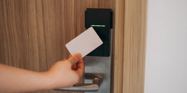 Hand holding card near door lock reader.