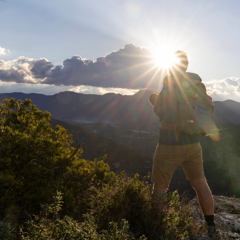 Mature man hikes along mountain path at sunrise, Liguria