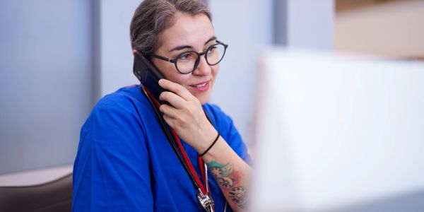Female healthcare worker talking on phone at computer.