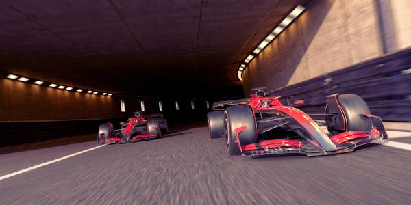 Two red Formula 1 cars racing through a tunnel at high speed.
