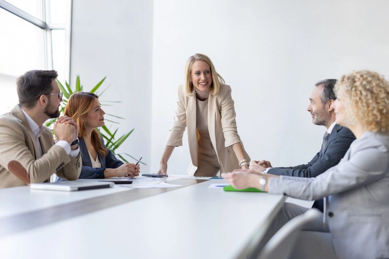 A confident woman leading an engaging business meeting with her team, showcasing collaboration and effective communication in a modern office.