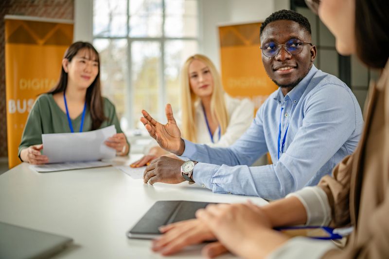 In a well-lit meeting room, a diverse group of business professionals participates in a discussion, sharing insights and collaborating on new ideas during an educational conference.