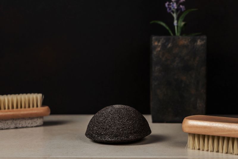 Black facial sponge on dark background. Spa and beauty cosmetics, facial cleansing.