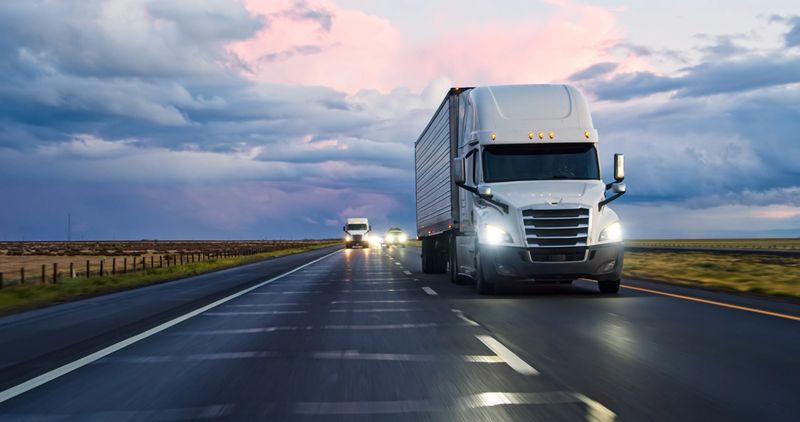 A semi-truck driving south on Interstate 5 in the Central Valley on a stormy evening.