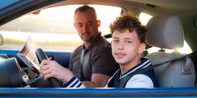 Father and son sitting in a car with seat belts on.