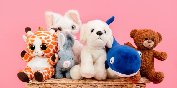 Collection of colorful stuffed animals against a pink background.