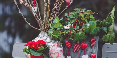Decorative plants and heart ornaments arranged on a gray outdoor table.