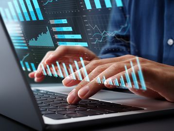 Person analyzing data charts on a laptop keyboard.