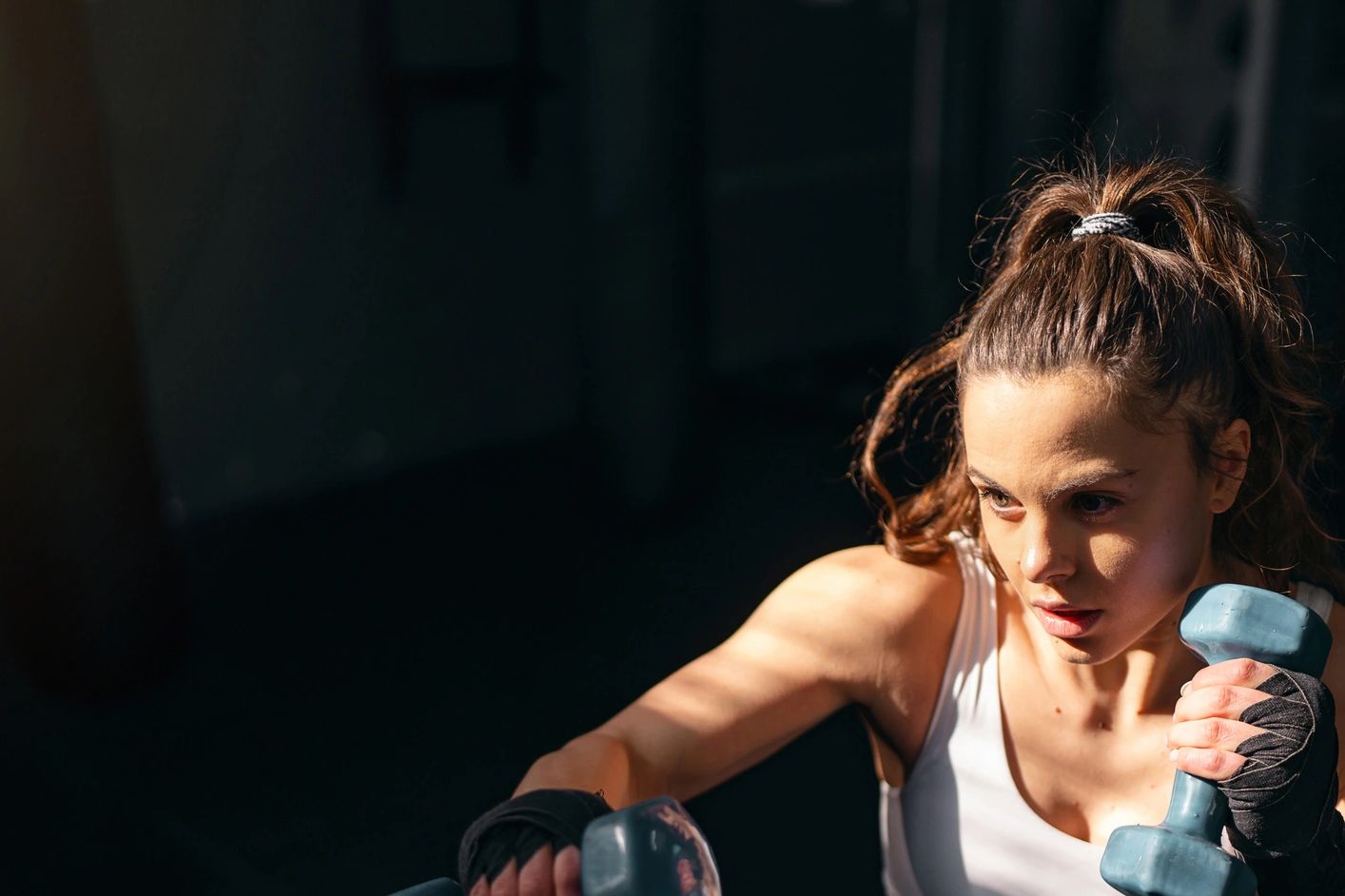 Woman intensely exercising with dumbbells in a gym.