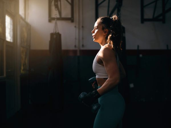 Woman exercising with dumbbells in gym.