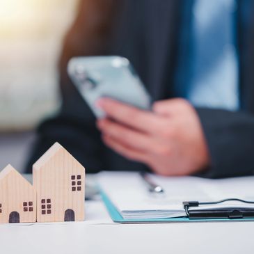 Mobile notary reviewing real estate documents on phone with small house models