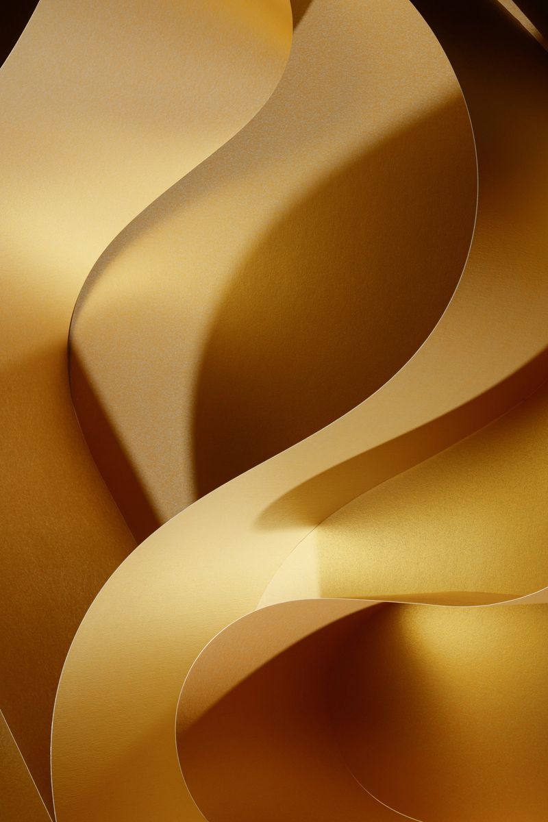 Abstract shapes concept design background from golden paper. Wavy pattern with light and shadow. Focus on an edge of the paper. No AI, real image