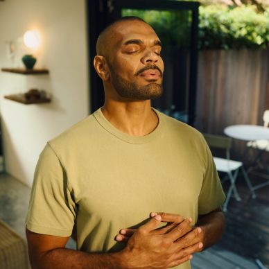 Man meditating with eyes closed in a peaceful indoor setting.