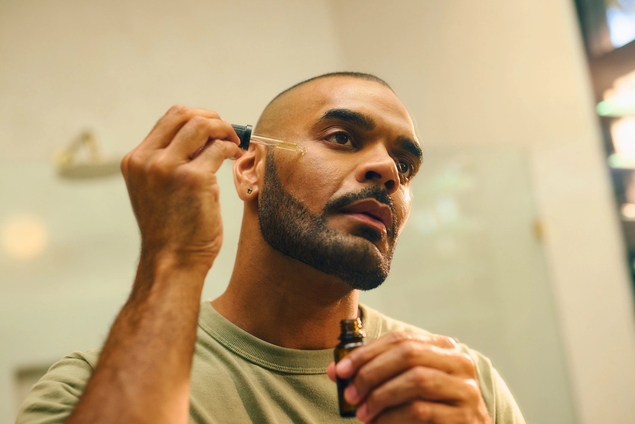 Man applying facial serum using a dropper.