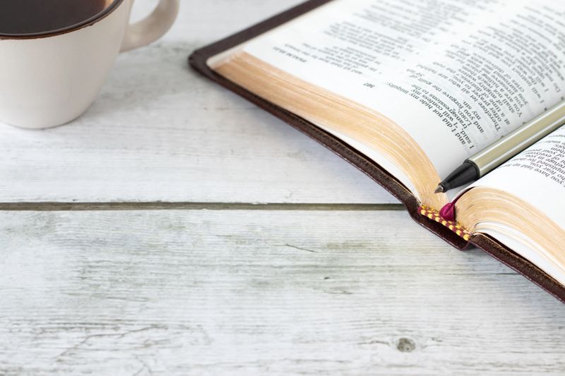 Open holy bible book with cup of coffee on wooden desk. Copy space. Scripture study and reading, Christian biblical concept.