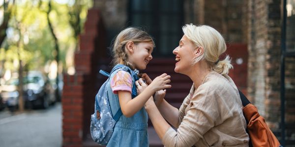 Mother joyfully greets her daughter outdoors.