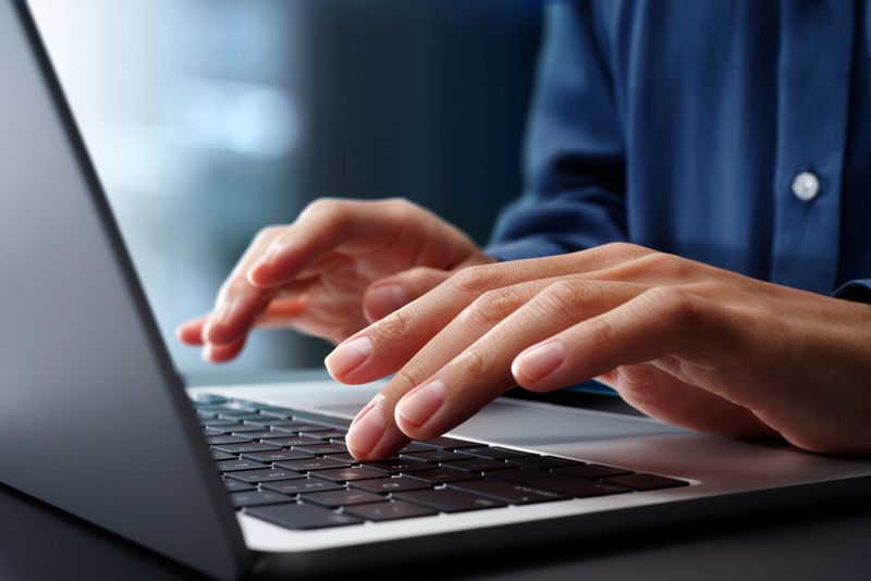 Closeup of Hands typing on laptop computer keyboard. Businessman working at desk in office. Using technologies in business.