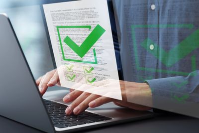 Person typing on laptop with digital checklist and green checkmarks overlay.