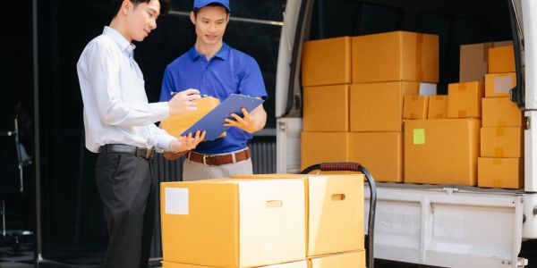 Two men checking delivery boxes near a truck.