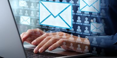 Person typing on a laptop with digital email icons floating above.