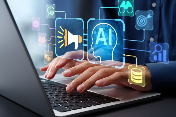 Hands typing on a laptop with AI and digital marketing icons floating above.