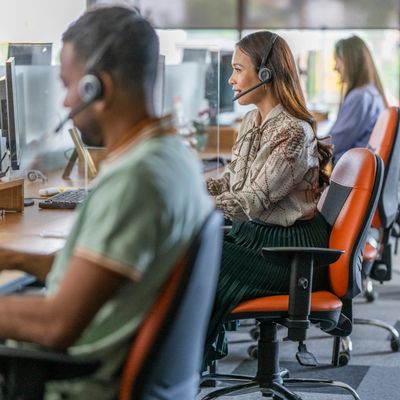 People working at call center desks wearing headsets.