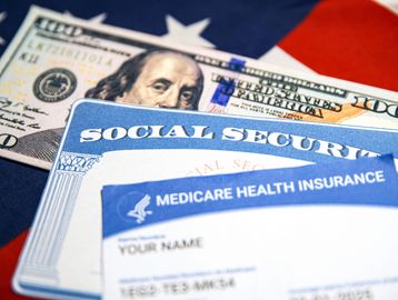 Social Security card, Medicare card, and $100 bill on an American flag.