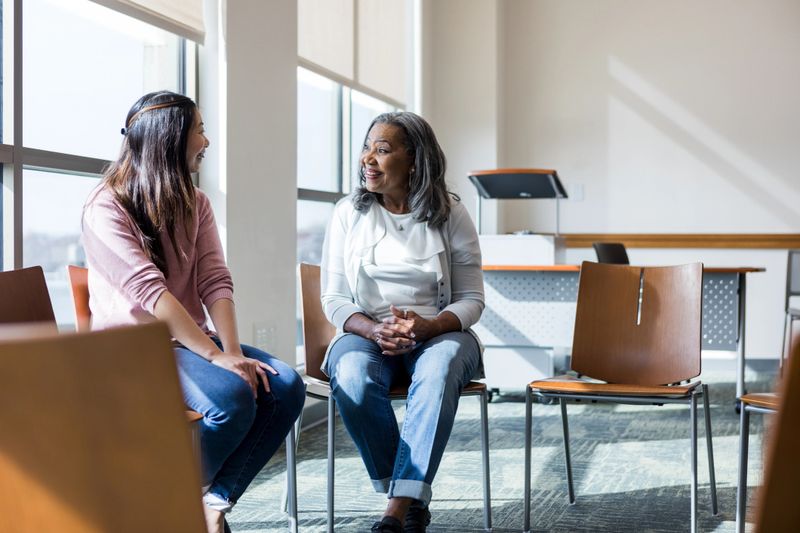 Multiracial women engage in conversation, showing happiness and friendship.