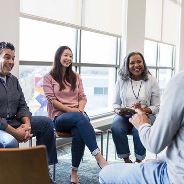 A group of four people engaged in a lively discussion in a bright room.