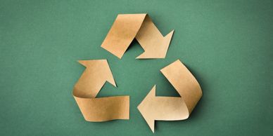 Recycle symbol made from brown paper on green background.