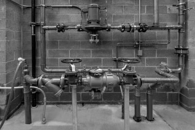 Industrial piping system with valves against a brick wall.