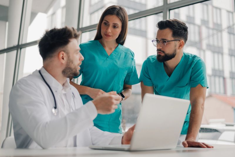 Doctors and nurses collaborating on patient's medical records using a laptop, enhancing healthcare through technology