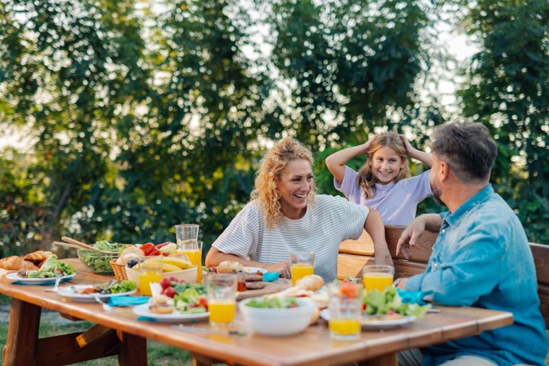 Cheerful family having a barbecue in their backyard, enjoying food and each other's company
