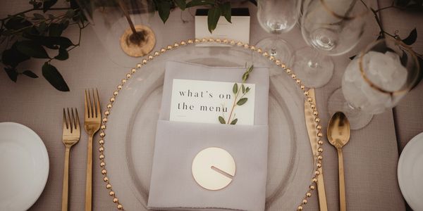 Elegant table setting with gold cutlery and a menu card.