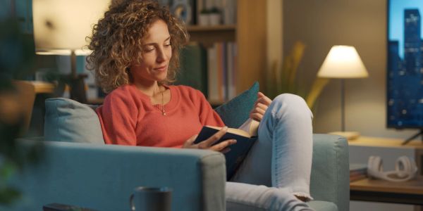 Woman reading a book on a couch at home.
