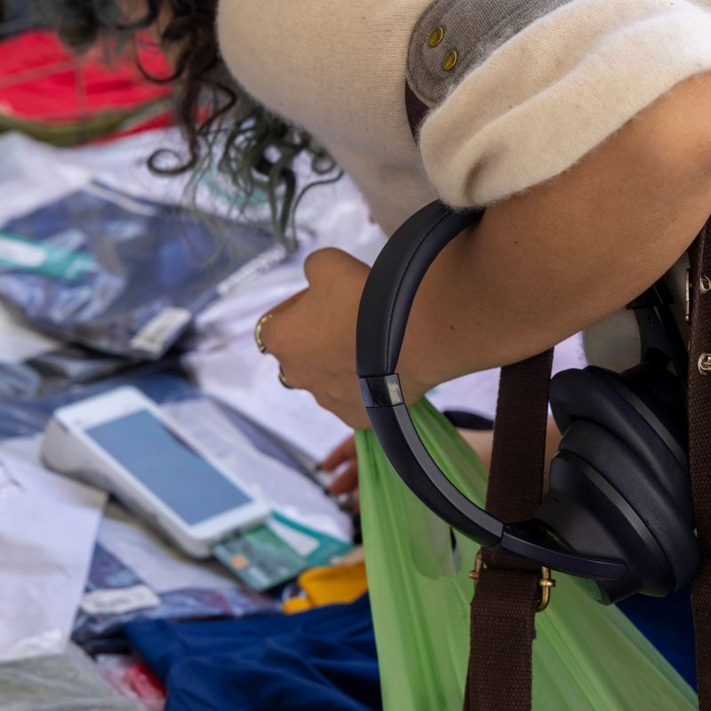 Young, mixed race, generation z, woman pays for clothing at outdoor market, Liguria