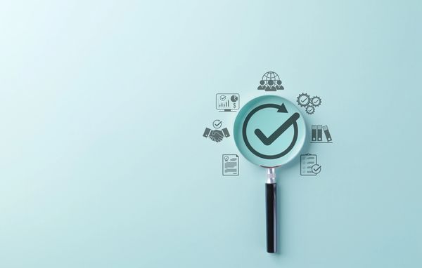 Magnifying glass highlighting a checkmark with business icons around it.