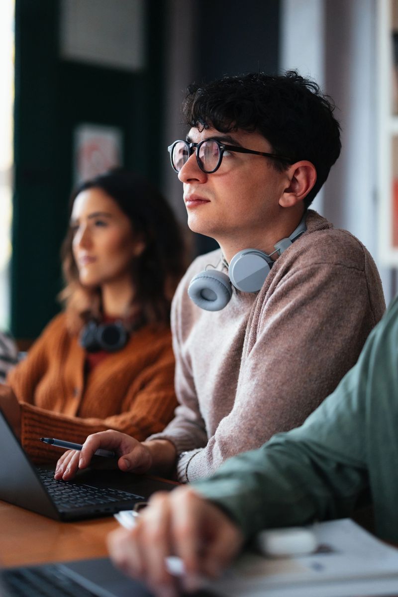 Students sitting together in a bright, contemporary space, using laptops and notebooks for study, conveying focus, collaboration, and a conducive learning atmosphere in a modern environment.