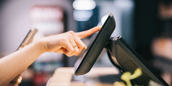 Person using a touchscreen point-of-sale system at a counter.