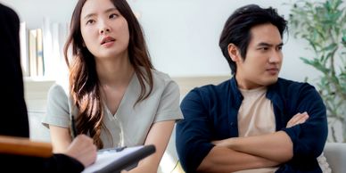 An asian woman and an asian man talk through communication issues in counseling.