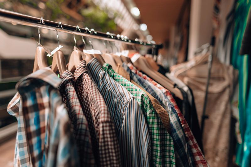 Displaying a vibrant assortment of shirts on hangers in a store specializing in used clothing, creating an eye-catching and textured showcase of fashion choices and styles