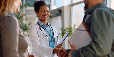 Doctor smiling and shaking hands with a patient.