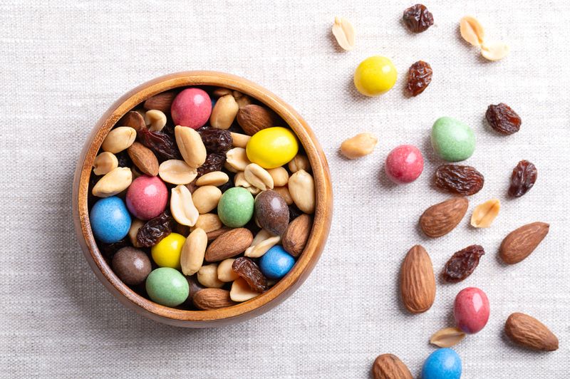 Rainbow trail mix in a wooden bowl on linen fabric.