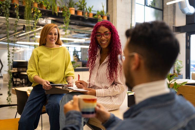 Multiracial colleagues enjoying a coffee break while discussing a project in a modern coworking space