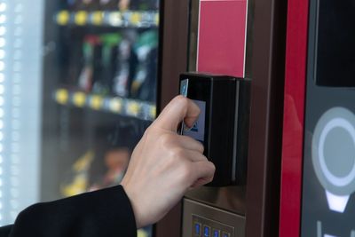 A person inserting a card into a vending machine's card reader.