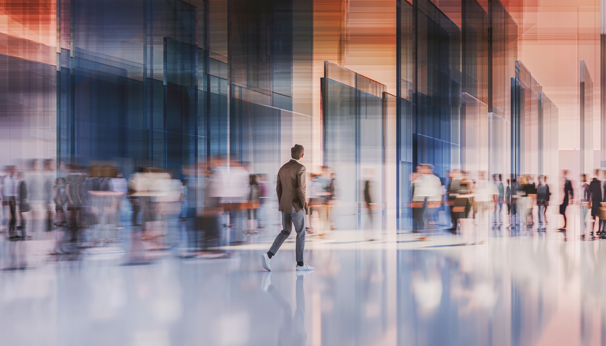 Man walking in a busy, modern glass building.