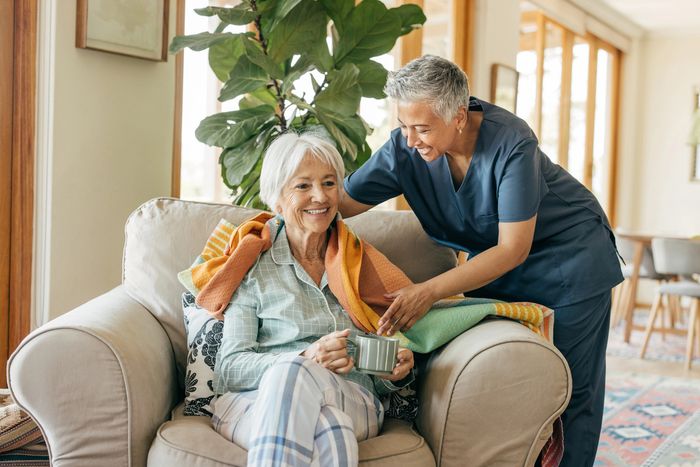 Four elderly friends smiling and enjoying time together indoors.