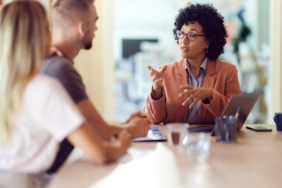 Businesswoman explaining something to a couple during a meeting.